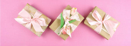 Gifts wrapped in kraft paper and pink ribbons overhead flat lay for Mothers Day, birthday or...