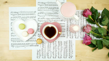 Feminine desk or workspace coffee break time overhead flatlay with sheet music and roses.の写真素材