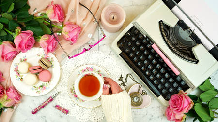Romantic vintage feminine writing scene, tea break with old typewriter and pink roses on marble table top down overhead.の写真素材