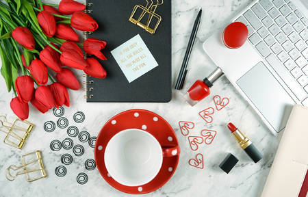 Modern stylish feminine desk or workspace coffee break with high tech touchscreen laptop and red female accessories.の写真素材