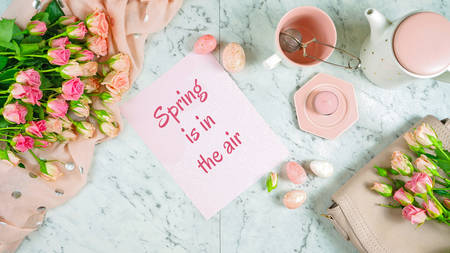 Welcoming Spring theme concept flat lay tea break with pink roses and female accessories on white marble background.の写真素材