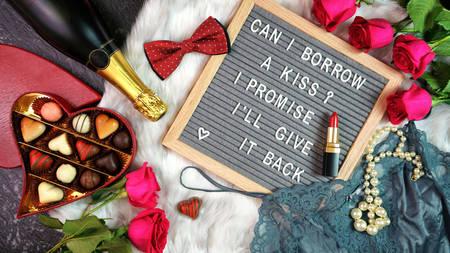 Valentines Day flat lay with roses, champagne and letterboard.