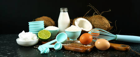 Coconut baking ingredients, coconut milk, flour, oil, and shredded coconut.