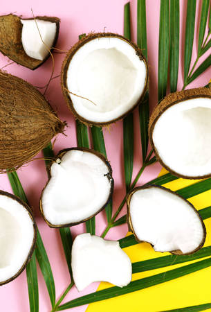 Coconut cut into pieces on modern colorful creative flat lay layout overhead.