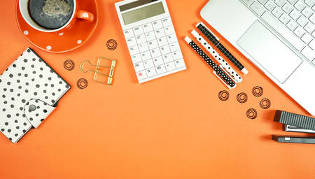Desktop workspace flat lay with hi-tech touch screen laptop and modern orange, black and white accessories on orange trend background. Negative copy space.の写真素材