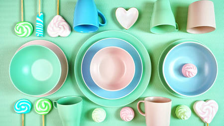 Modern pastel pink, green and blue ceramic tableware on pale green.の写真素材