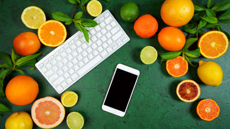 Citrus fruit on textured green background workspace blog hero header flat lay.