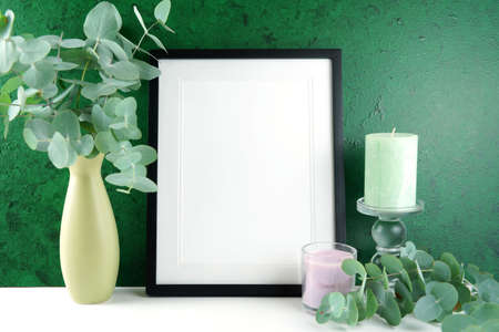 Picture Frame Mock up against a dark green background with eucalyptus leaves