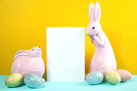 Easter product mockup with pink bunnies, easter eggs against yellow background.の写真素材