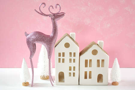 Pink Christmas reindeer and village houses ornaments still life.の写真素材