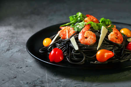 spaghetti negro, italian black pasta with seafood, with shrimp, cheese, tomato, horizontal, black backgroundの写真素材