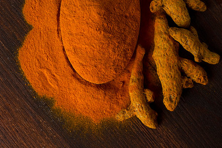Turmeric powder and root on a wooden table, top view. no people,