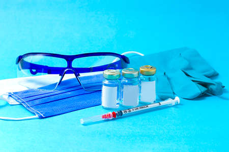 Medical concept, vaccination, vials, with an insulin syringe, and protective equipment , on a blue background, no people,horizontal,の写真素材