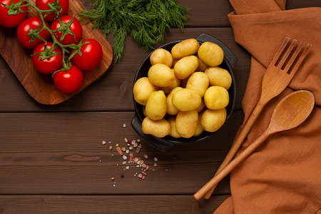 young potatoes, raw, in a cast iron skillet, on a wooden background, top view, horizontal, food, rustic potato, small potatoes, herbs, dinner, skillet, small, baby, new potatoes, potatoes, color, lotsの写真素材