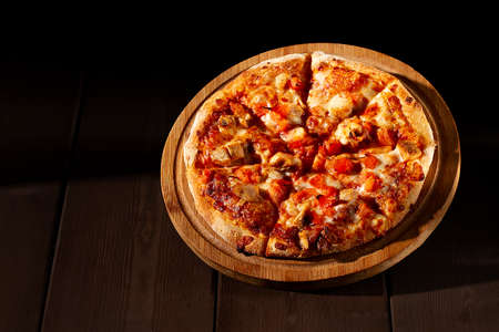 pizza, on a wooden board, with bbq chicken, mozzarella, roasted garlic and marinara sauce, on a brown blackground,の写真素材