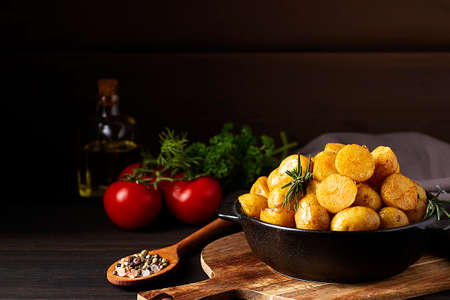fried young potatoes, in a cast iron skillet, on a wooden background, top view, horizontal, food, rustic,の写真素材