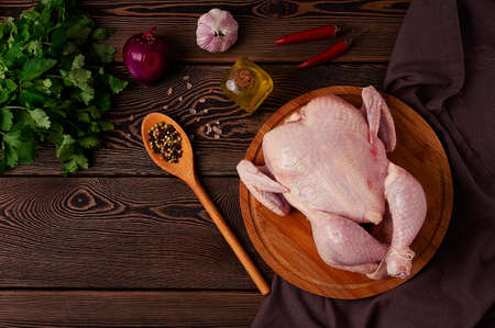 Raw chicken carcass on a cutting board, with cooking ingredients, top view, wooden table, horizontal, no people,の写真素材