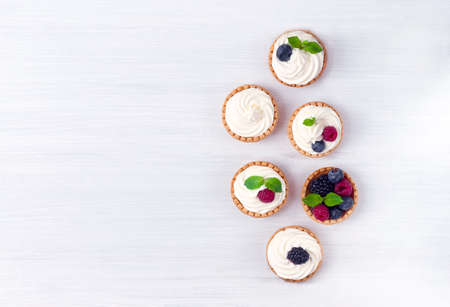 Mini tartlets with whipped cream and fresh berries, on a white table, blurred focus, horizontal, no people,の写真素材