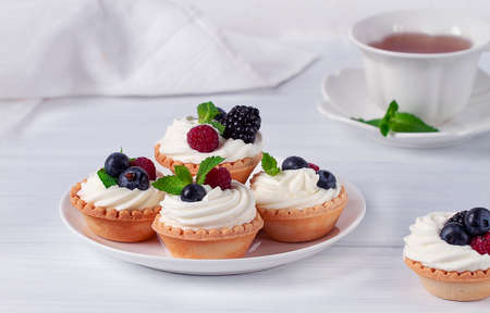 Mini tartlets with whipped cream and fresh berries, on a white table, blurred focus, horizontal, no people,の写真素材