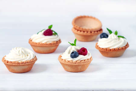 Mini tartlets with whipped cream and fresh berries, on a white table, blurred focus, horizontal, no people ,. High quality photoの写真素材