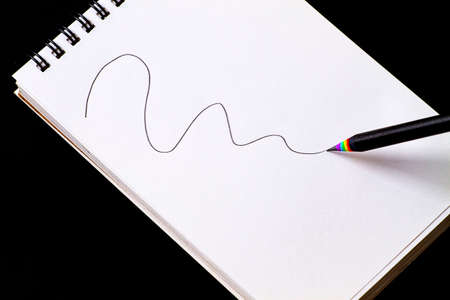 black simple pencil, with multicolored shavings, rainbow colors, on a white notebook with a spring,...