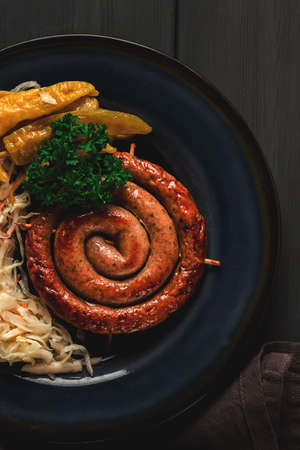 Traditional German dish, Fried spiral sausage, with sauerkraut, with red sauce, on a dark gray wooden background, top view, horizontal, no people,の写真素材