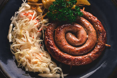 Traditional German dish, Fried spiral sausage, with sauerkraut, with red sauce, on a dark gray wooden background, top view, horizontal, no people,の写真素材