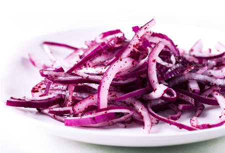 Sliced into half rings red onion, with Sumac spice, on a white background, no people,の写真素材