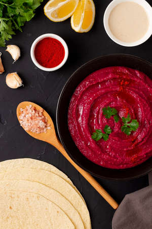 Beetroot hummus, with tahini, spices and olive oil, on a black background, no people, top view,....