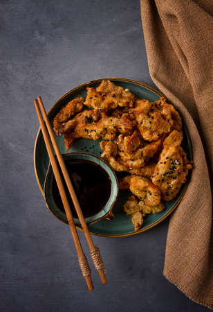 Fried meat in deep-fried batter, with sesame seeds, and soy sauce, on a gray table, there are no people,の写真素材