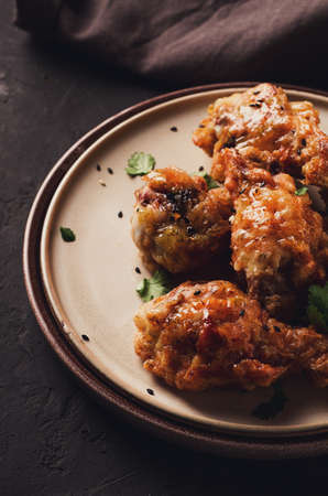 Fried chicken legs breaded, with spices and herbs, on a dark background, vertical, no people,...