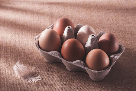 Fresh eggs in a cardboard box, on a beige background, no people, rustic style, selective focus, raw,...
