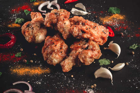 Fried chicken legs breaded, with spices and herbs, on a dark background, horizontal, no people, selective focus, toned.の写真素材