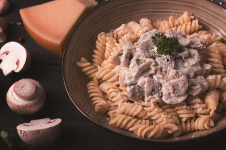 Fusilli pasta with champignons in cream sauce, top view, with ingredients, on a wooden table, no people,の写真素材
