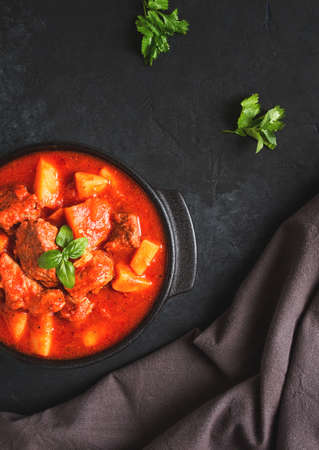 Stew with potatoes in tomato sauce, with spices and herbs, close-up, no people, on a black backgroundの写真素材