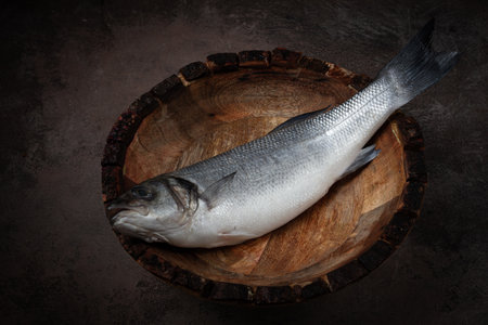 fresh, raw sea bass fish, in a wooden plate, top view, no people.の写真素材