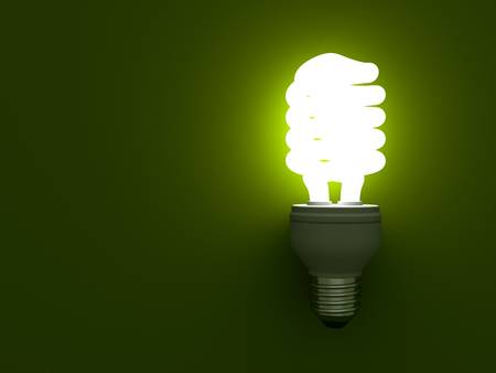 Eco energy saving compact fluorescent light bulb glowing on greenの写真素材