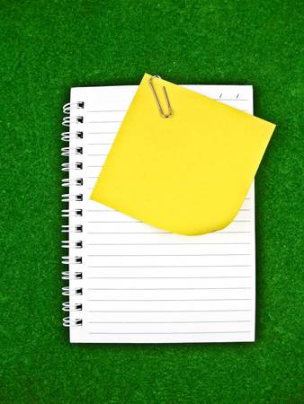 Yellow note and Notebook Paper on green backgroundの写真素材
