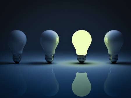 One glowing light bulb standing amongst the unlit incandescent bulbs with reflection , the different conceptの写真素材