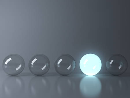 One blue glowing light ball standing out from the unlit glass balls on dark grey background with reflection and shadow , individuality and different creative idea concepts . 3D rendering.の写真素材