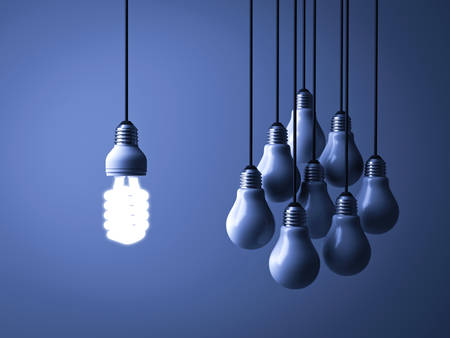 One hanging eco energy saving light bulb glowing and standing out isolated from unlit incandescent bulbs on dark blue background , leadership and different creative idea concept. 3D rendering.の写真素材