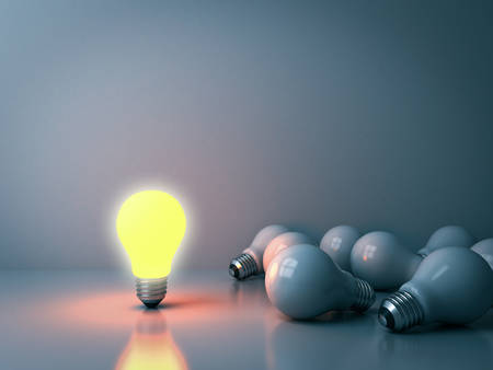 One glowing light bulb standing out from the unlit incandescent bulbs in the dark room background with reflections leadership and different business creative idea concepts 3D renderingの写真素材