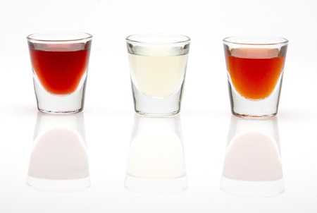 three different shot drinks in a row isolated on white backgroundの写真素材