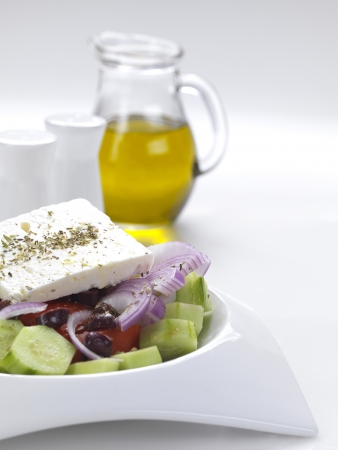 a traditional greek salad with feta cheese,tomatoes,cucumber,onion slices,olive slices,oregano and virgin olive oilの写真素材