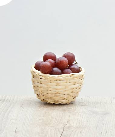 small basket with red grape on an antique tableの写真素材