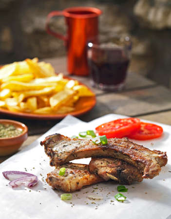 delicious lamb chops, served on a baking paper,as the greek tradition says, together with fried fresh potatoes and red wineの写真素材