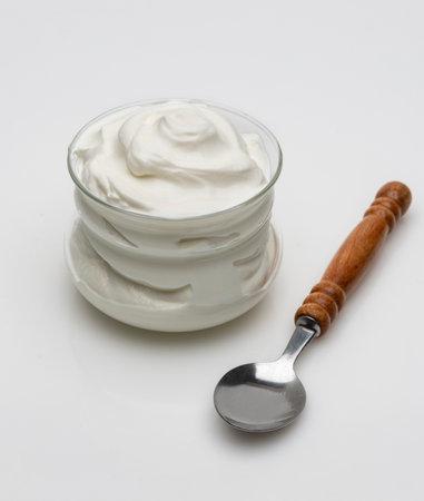 a bowl of greek yogurt on a white background.A wooden spoon is in it as well, ready to serve.の写真素材