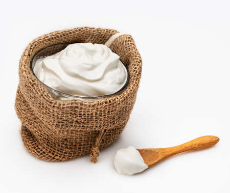a bowl of greek yogurt in a small rustic sack on a white backgroundの写真素材