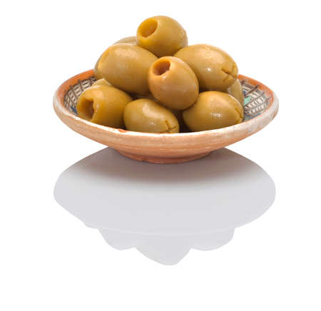 pitted green olives in a small traditional ceramic plate on a white backgroundの写真素材