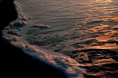 The waves leading edge reflects the colorful morning sunrise.の写真素材